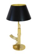 A Philippe Starck gilt metal Kalashnikov table lamp, with gothic inscription happiness is a hot