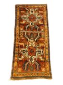 A Kazak red ground rug, with central medallions and geometric motifs, multi-bordered, 240 x