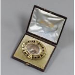A Victorian yellow metal and black enamel oval memorial brooch, in original box, with plaited hair