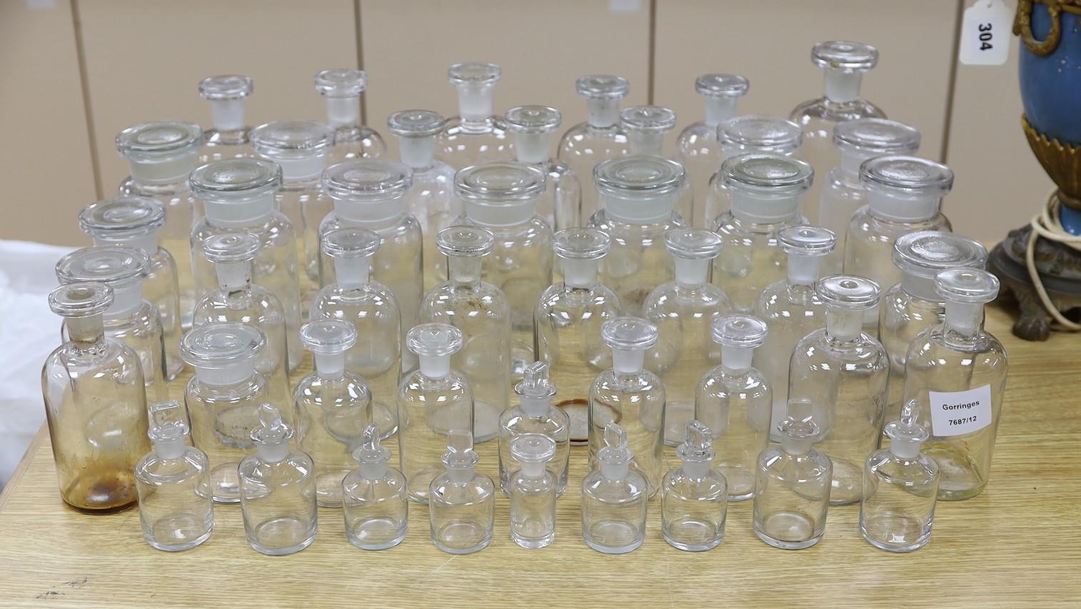 A large collection of clear glass chemist's bottles