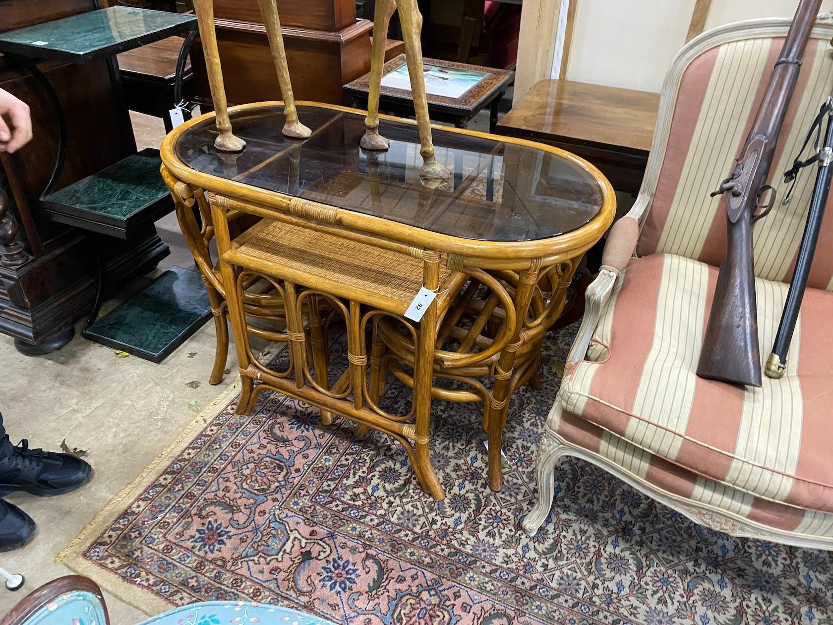 A caned bamboo and smoked oval glass top table, length 110cm, depth 56cm, height 73cm and a pair