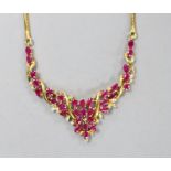 A modern Thai yellow metal, oval cut ruby and diamond chip cluster set necklace, 40cm, gross 22.6