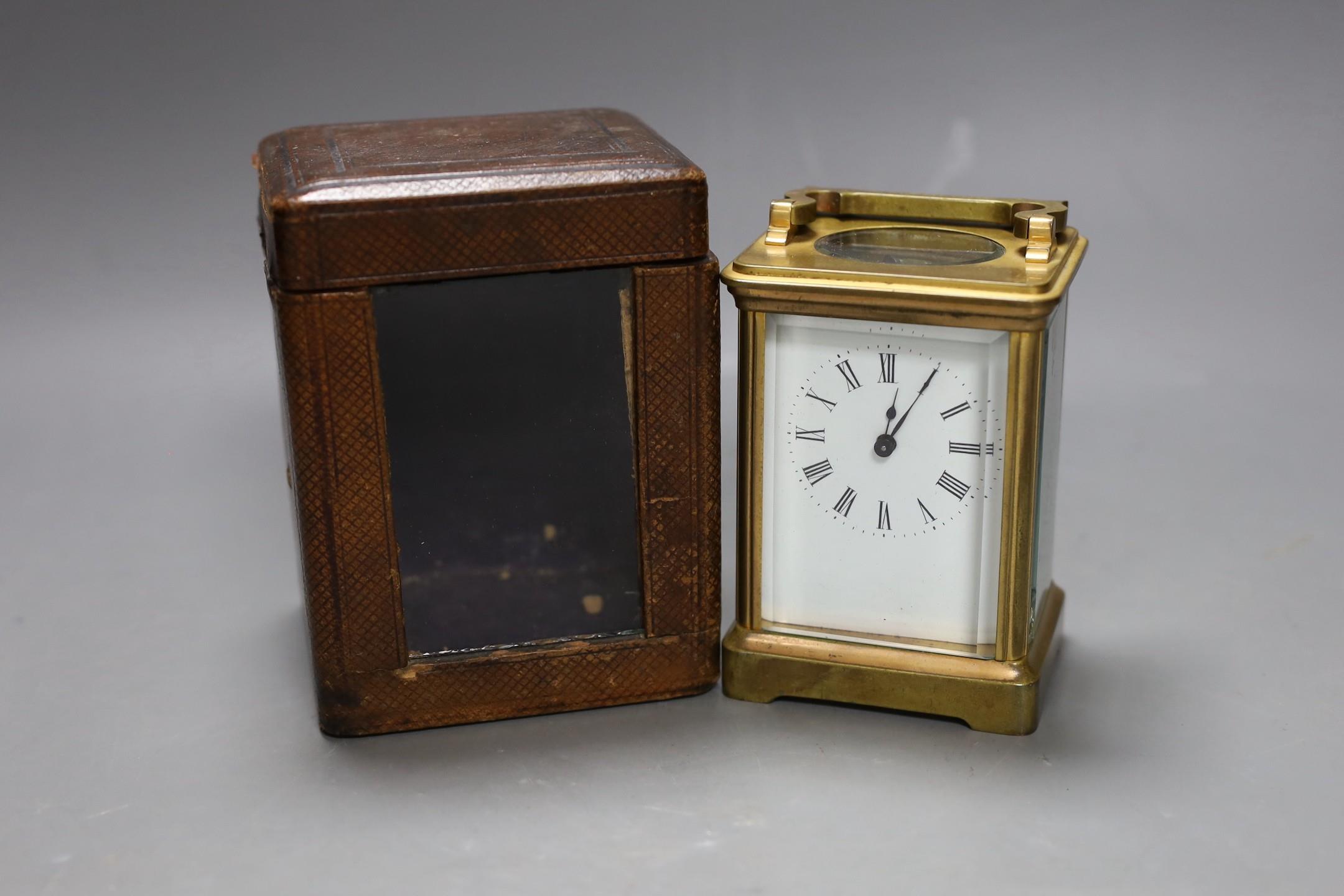 A leather cased brass carriage timepiece. 13cm tall