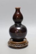 A Chinese brown monochrome double gourd vase (on stand). 19cm tall