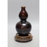 A Chinese brown monochrome double gourd vase (on stand). 19cm tall