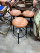 A set of three wrought iron and tan leather stools, height 64cm