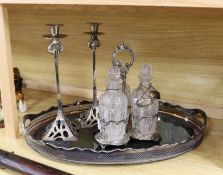 An oval silver plated tray, a three bottled tantalus and a pair of candlesticks, a silver ‘