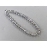 A modern 375 white metal and blue topaz line bracelet, 20cm, set with thirty two stones, gross