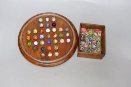 A mahogany solitaire board and marbles