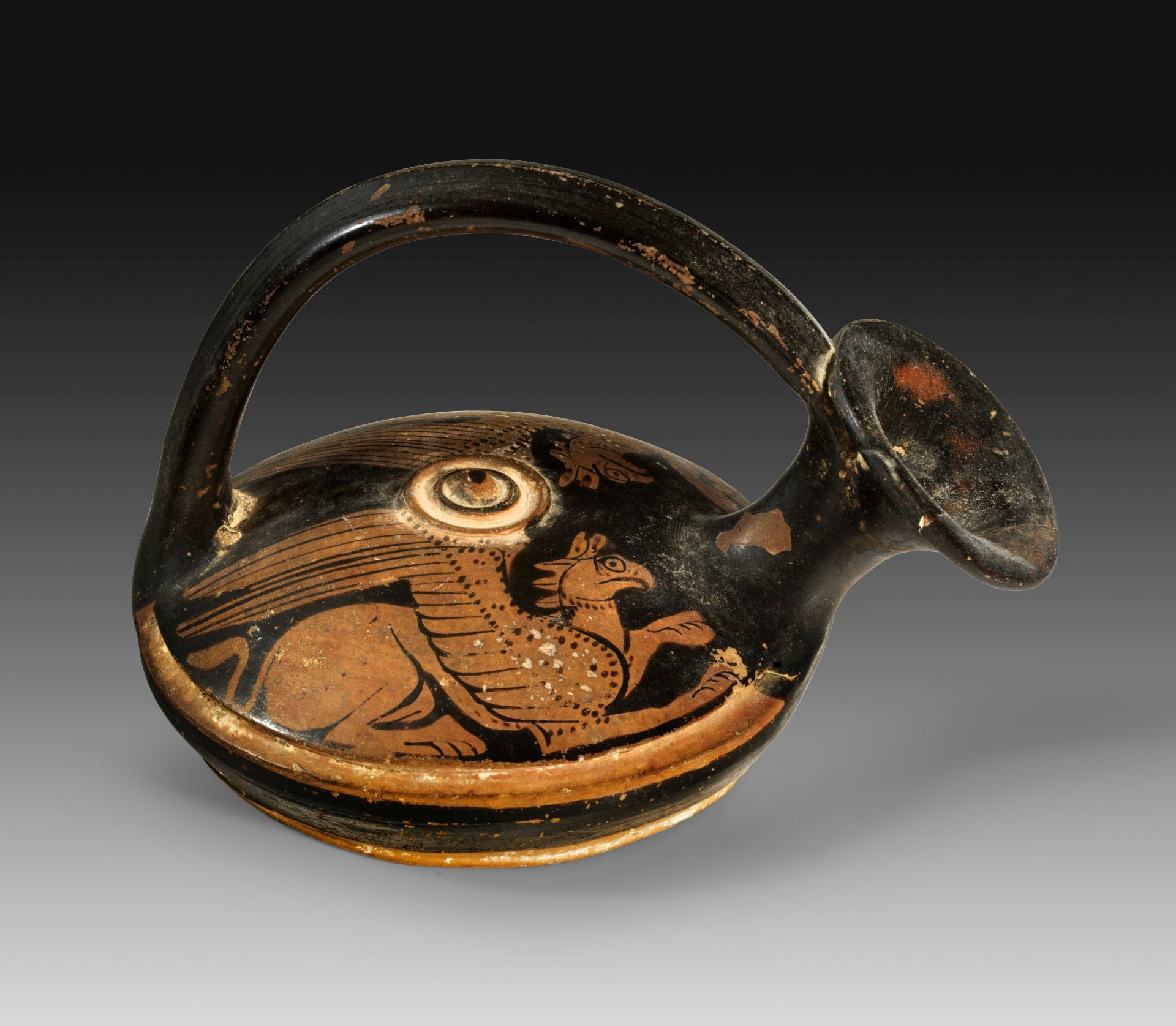 Attic red-figure askos with stirrup handle and pseudo lid painted with two lying griffins. 