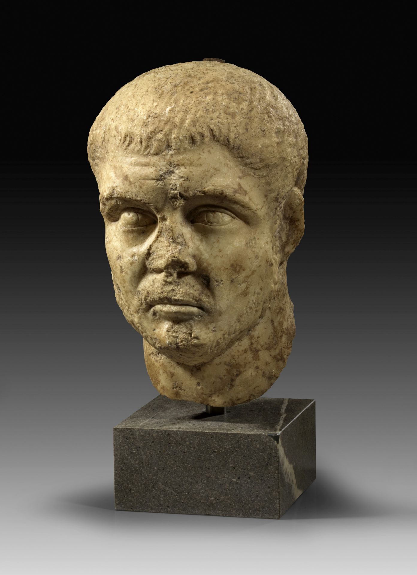 Marble portrait of young roman man with short beard.