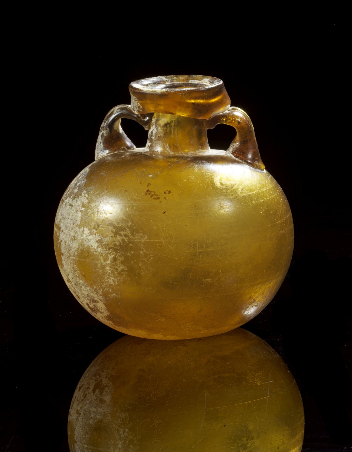 Large aryballos of clear glass in bronze yellow. 