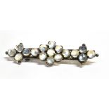 A VICTORIAN MOONSTONE BROOCH The white metal bar brooch set with 16 round glass 'Moonstone'
