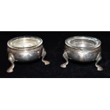 A PAIR OF SILVER CRUETS with clear glass liners of plain form with three splayed feet, faded