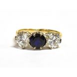 A 9CT GOLD BLUE SAPPHIRE AND CLEAR PASTE THREE STONE DRESS RING the central facetted round cut