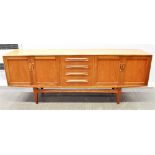 A 1960S TEAK SIDEBOARD with four drawers flanked by two door cupboards, 213cm wide 46cm deep 80cm