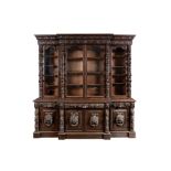 A FLEMISH OAK CARVED BREAKFRONT BOOKCASE CABINET having a carved cornice above a central glazed twin