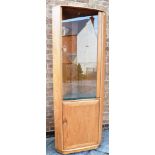 A LIGHT ERCOL CORNER DISPLAY CABINET the upper glazed section fitted with three adjustable