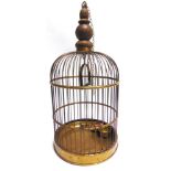 A BRASS BIRD CAGE with a sliding access panel and two brass feed bowls, overall 61cm high (inclusive