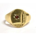 A VINTAGE 9CT GOLD STAR SET SIGNET RING The bezel set with a red paste stone with a hammered pattern