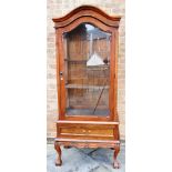 A HARDWOOD DISPLAY CABINET with domed top, the bevelled glazed door and side panels enclosing two