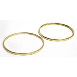 TWO YELLOW METAL BANGLES The bangles of similar hollow hoop design with push clasps, marked 585