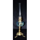 AN EARLY 20TH CENTURY CONTINENTAL OIL LAMP with blue glass reservoir, the brass base with three