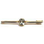 A MARKED 15CT AQUAMARINE BAR BROOCH the centrally set aquamarine measuring 0.9cm by 0.6cm, the