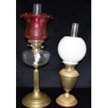 AN EDWARDIAN TWIN BURNER OIL LAMP with cranberry glass shade and clear glass reservoir, on reeded