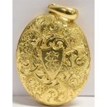 A LARGE OVAL YELLOW METAL LOCKET The locket with chased floral and foliate scroll, a monogrammed