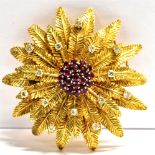 AN 18CT GOLD DIAMOND AND GARNET TIERED BROOCH the brooch of a floral shape set with textured gold
