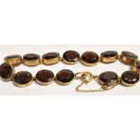 A GARNET BRACELET The bracelet comprising of 14 faceted oval garnets each mounted in gilt, the