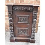 AN OAK CORNER CABINET the inverted breakfront with carved frieze above door with two carved