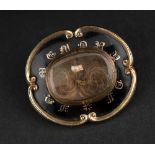 A MID VICTORIAN MEMORIAL BROOCH the black enamel brooch set with a glass fronted compartment