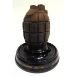 A NOVELTY INKWELL IN THE FORM OF A HAND-GRENADE complete with white ceramic liner, set to a circular
