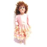 A KLEY & HAHN BISQUE SOCKET HEAD DOLL with a replacement curled brown wig, fixed blue glass eyes,