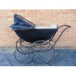 A BABY'S PRAM the lined black wood body with a folding rexine hood, and a cream padded interior, the