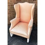A WING ARMCHAIR WITH SHAPED BACK AND SCROLL ARMS on painted supports with H-shape stretcher