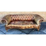 A BUTTON UPHOLSTERED LEATHER CHESTERFIELD SOFA with scroll arms and serpentine seat, suitable for