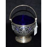 A PIERCED SILVER BASKET with handle on a pedestal base with blue glass liner, hallmarked for