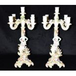 A PAIR OF CONTINENTAL COLOURED BISQUE FIGURAL FIVE LIGHT CANDLESTICKS each with floral decoration