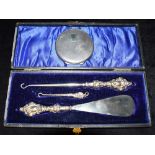 A SILVER LADIES COMPACT together with a cased set of silver topped implements (shoe horn, button