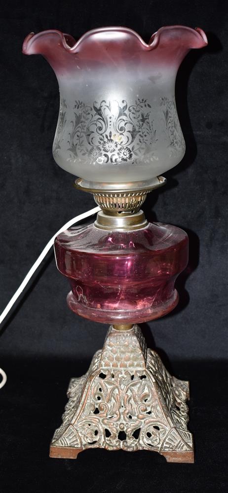 AN EDWARDIAN OIL LAMP CONVERTED TO ELECTRICITY with cranberry glass reservoir and shade with