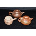 THREE CHINESE YIXING TEAPOTS two with impressed seal marks to base, the largest 9cm high Condition