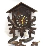 A BLACK FOREST CUCKOO CLOCK with twin cast iron pine cone weights, the movement striking on a coiled