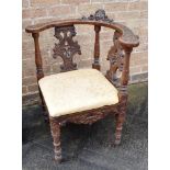 A CARVED OAK CORNER ARMCHAIR the top rail carved with a cherubs face, pierced and carved splats