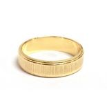 A STAMPED 750 YELLOW METAL BAND RING the ring with textured pattern with shank marked 750 A1, ring