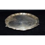 A SILVER SALVER With shaped pie crust border on three ammonite feet, the tray hallmarked for