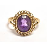 A 9CT GOLD AMYTHEST COCKTAIL RING The oval faceted amethyst measuring 1 x 0.8 cm raised in a fancy