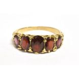 A 9CT GOLD GARNET FIVE STONE DRESS RING The ring set with five graduated garnets, the largest